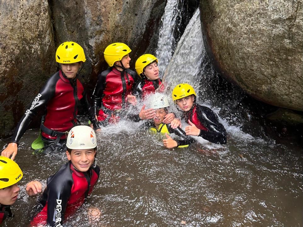Grupo dentro de una poza con una cascada cayendo encima