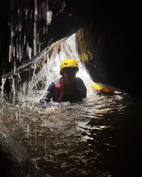 Persona dentro de una cueva de barranco, detrás de una cortina de agua