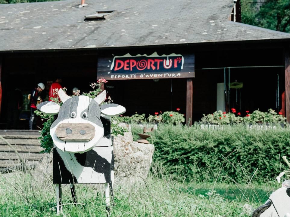 La base de Deportur en Les, con el cartel y la vaca de madera