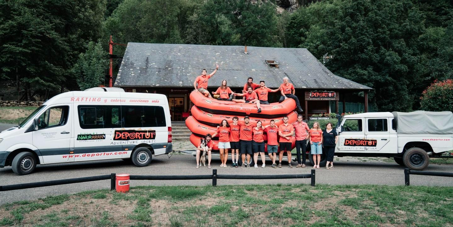 El equipo de Deportur delante de la base de Les, con las barcas apiladas y las furgonetas