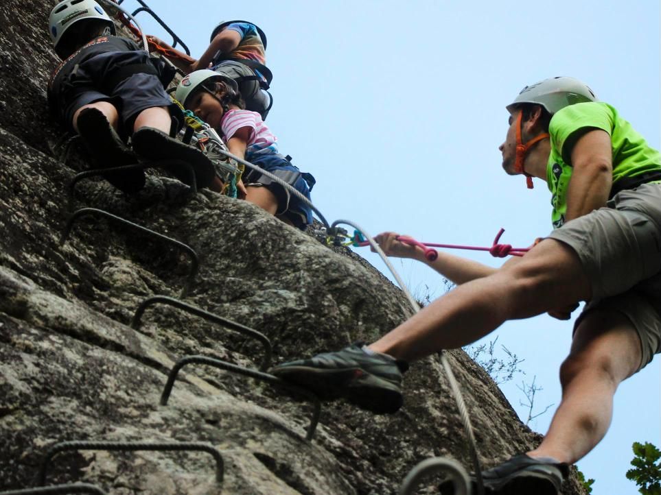 Monitor de Deportur ayudando a una niña a subir por las grapas de la ferrata
