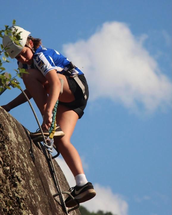 Una chica sube por la vía ferrata con el cielo de fondo