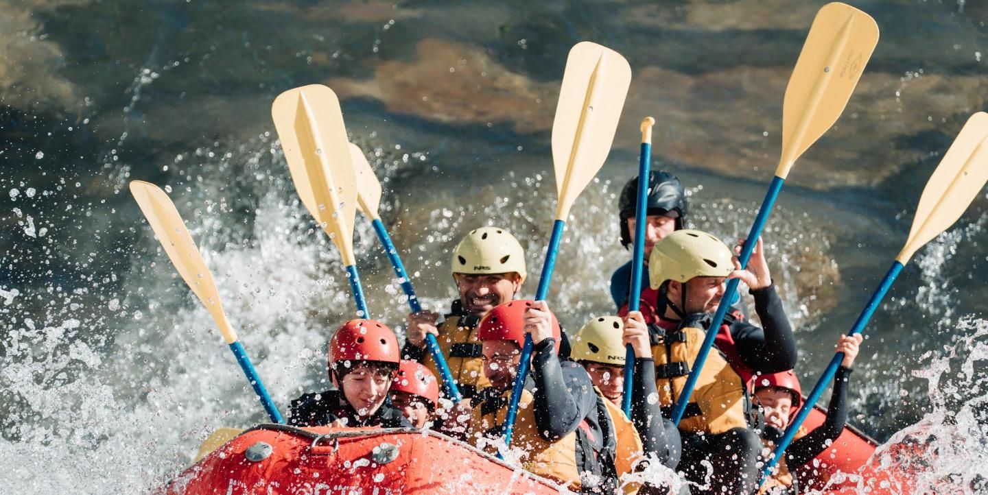 Una barca de rafting de Deportur entra en un rápido del Garona con los remos en alto