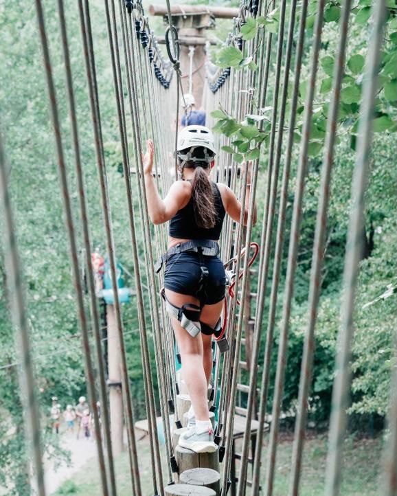 Una chica cruza un puente colgante entre los árboles de Naturaran