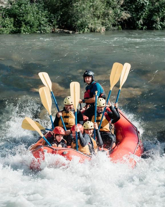 Barca de rafting con un grupo y su guía en pleno rápido